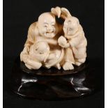 Japanese carved ivory figure of Hotei holding a fan with two small children, signed to base,