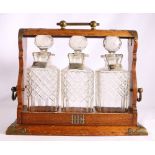 Oak three decanter tantalus initialled HH, each decanter with labels for Whisky,