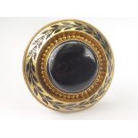 Victorian gold circular brooch with onyx cabochon and a border of black enamel leafage.