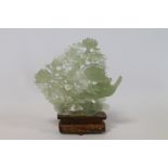 Modern Chinese green hardstone pierced carving of birds amongst peonies, on carved wooden base,