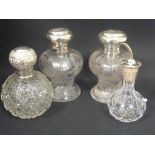 Pair of engraved glass toilet bottles with embossed silver caps by Comyns, another globular,