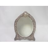 Edwardian silver toilet mirror of oval shape, the embossed and pierced mount with putti, scrolls,