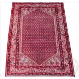 A Persian Hamadan wool rug, worked with a Sarouk Mir design against a red ground,