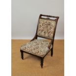 An Edwardian walnut upholstered salon chair, with turned legs on castors,