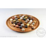 A large oak solitaire board with thirty eight agate gaming marbles,