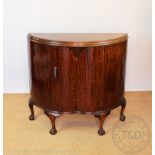 An Art Deco walnut bow front cupboard, with shaped door, on cabriole legs with claw and ball feet,