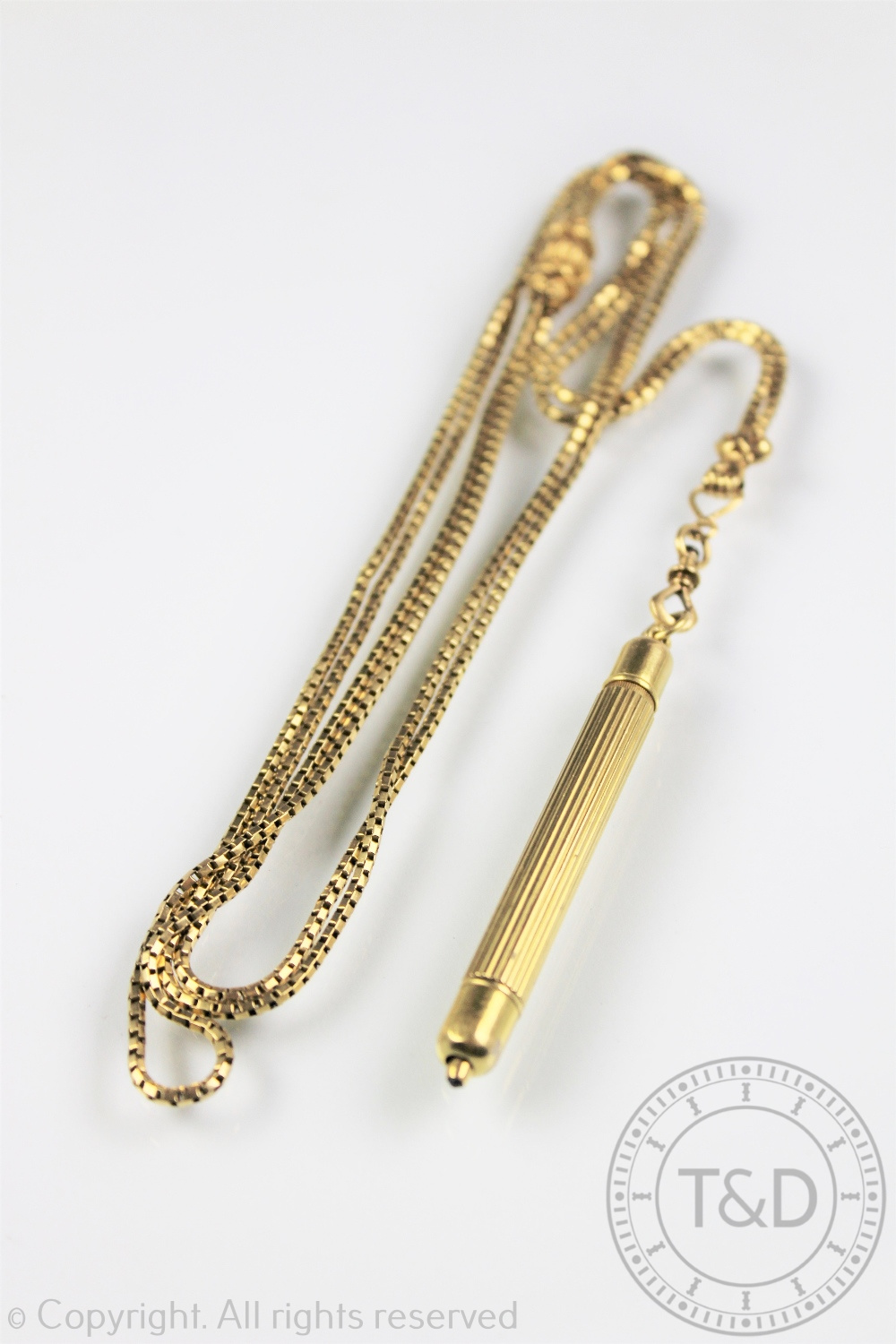 A Victorian yellow metal long chain with attached propelling pencil,