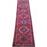 A Caucasian Hamadan wool runner, worked with seven geometric gulls against a red ground,