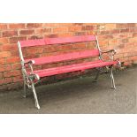 A cast iron and red painted wood garden bench, on scroll legs,