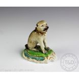 A Staffordshire model of a pug, 19th century, modelled upon a scroll base and painted,