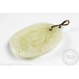 A carved jade pendant, the lozenge shaped panel carved with moths, flowers and foliage,