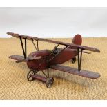 A large vintage painted model of a bi-plane, with pilot, red livery,