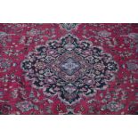 A Persian Mashad wool carpet, worked with an all over floral design against a red ground,