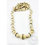 An Indian graduated ivory bead necklace, circa 1920, each bead with geometric banding,