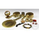 An Indian brass part dressing table set comprising three bruches and a hand mirror,