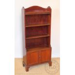 An Edwardian mahogany waterfall bookcase, with three shelves above two cupboard doors,