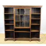 A 1920's oak bookcase, with a central glazed door around three sections with adjustable shelves,