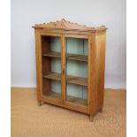 A late 19th century pine display cabinet, with two glazed doors, enclosing shelves, on shaped legs,