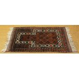A Caucasian wool prayer mat / rug, worked with geometric patterns against a pale red ground,