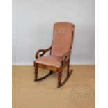 A Victorian stained beech rocking chair, with carved scroll arms, pink upholstery,
