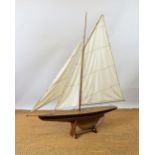 A large pond model sailing boat with single rigged mast, partially brown painted gloss finish hull,