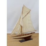 A large pond model sailing boat with single rigged mast, partially cream painted gloss finish hull,