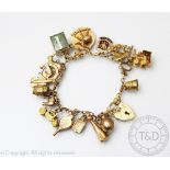 A yellow metal bracelet hung with numerous 9ct gold and gold coloured charms including a locomotive,