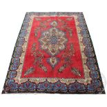 A Persian Tabriz type wool carpet, worked with an elaborate floral medallion against a red ground,