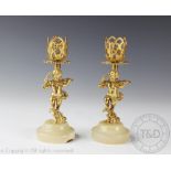 A pair of 20th century figural candlesticks, each modelled as a gilt cupid on a circular onyx base,