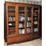 A breakfront walnut and stained wood bookcase, with four glazed doors enclosing shelves,