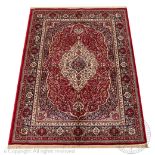 A Kashmir rug, worked with an ivory medallion against a red ground, with all over foliate detailing,