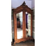 A French 18th century style carved walnut armoire, with two mirrored doors enclosing shelves,