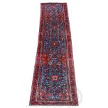 A Persian wool runner, worked with a floral design against a blue ground,