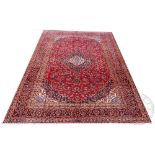 A large Persian Kashan type wool carpet, worked with an all over floral design against a red ground,