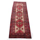 A Persian Heriz type wool runner, worked with three geometric red gulls against a beige ground,