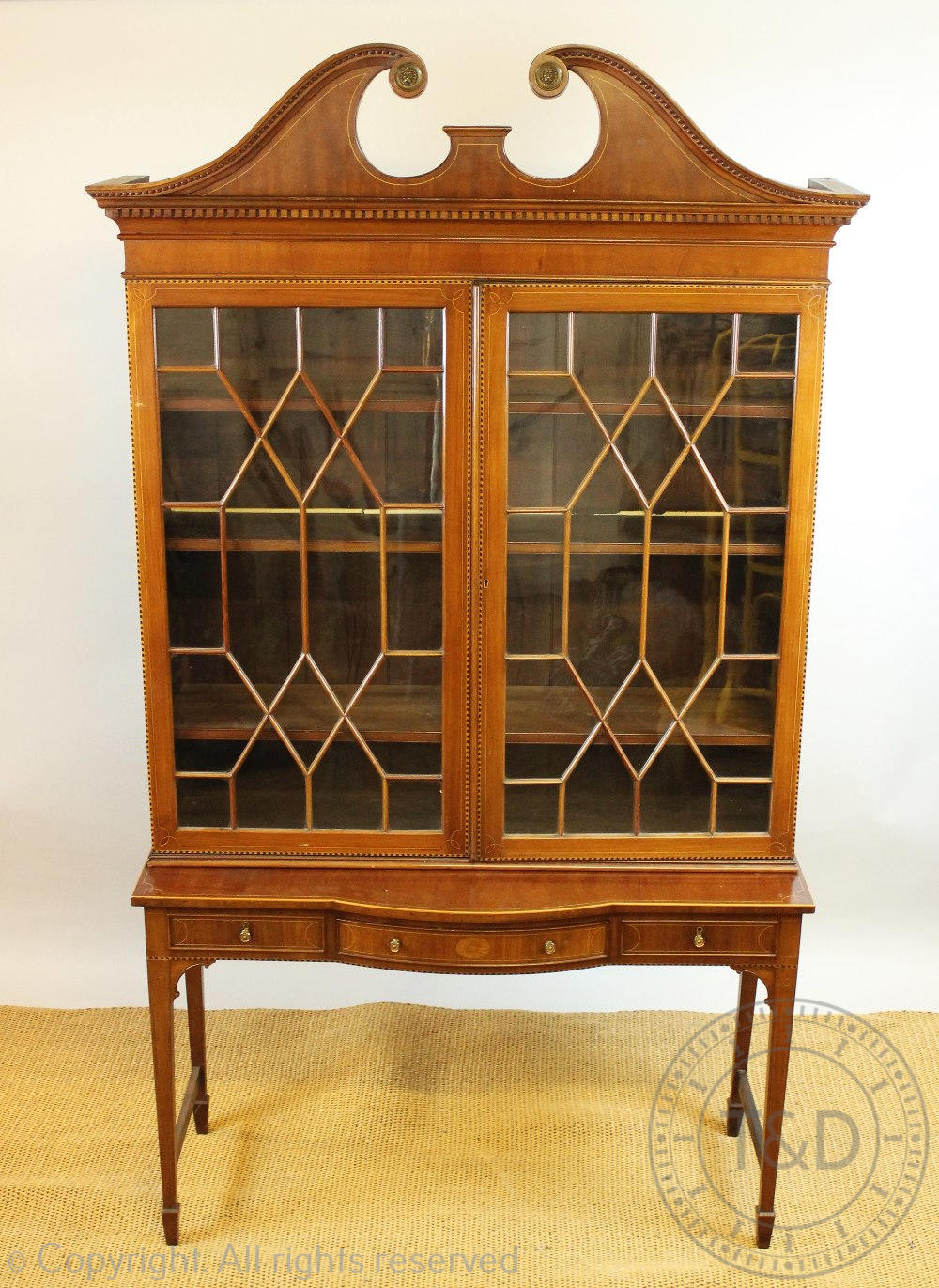 An Edwardian inlaid display cabinet, with astragal glazed doors below a swan neck pediment,