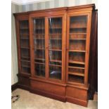 A breakfront walnut and stained wood bookcase, with four glazed doors enclosing shelves,