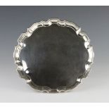 A silver salver, the circular shaped salver with pie crust moulded rim on three ball and claw feet,
