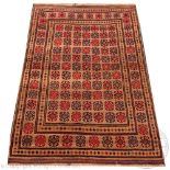 A Baluch hand woven wool carpet, worked with red and blue geometric gulls against a beige ground,