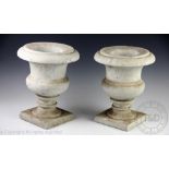 A pair of marble urns, each of campana form with stepped stems and sqaure bases,