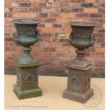 A pair of 19th century style cast iron campana urns on stands, with cast floral detailing,