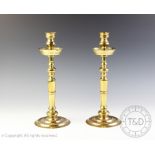 A pair of heavy gauge brass candlesticks, of baluster form and with integral drip tray,