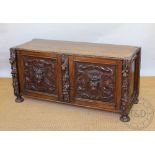 A Victorian carved oak low cupboard, converted from a buffet, the doors decorated with beasts,