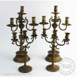 A pair of early 20th century brass three branch candelabra on turned baluster stems and circular