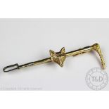 An Alabaster and Wilson yellow gold and silver stock pin designed as a riding crop and foxes mask,