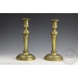 A pair of 19th century brass candlesticks, each with fluted columns and with acanthus detailing,