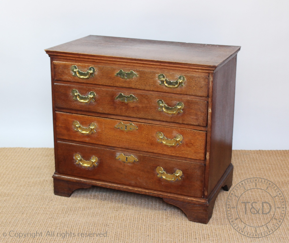 A George III oak chest, of four graduated long drawers, with later brass handles, on bracket feet,