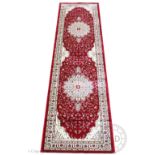 A Kashmir runner, worked with two white floral medallions against a floral red ground,