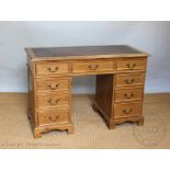 A Victorian style pine pedestal desk, with leather inset top above and arrangement of nine drawers,