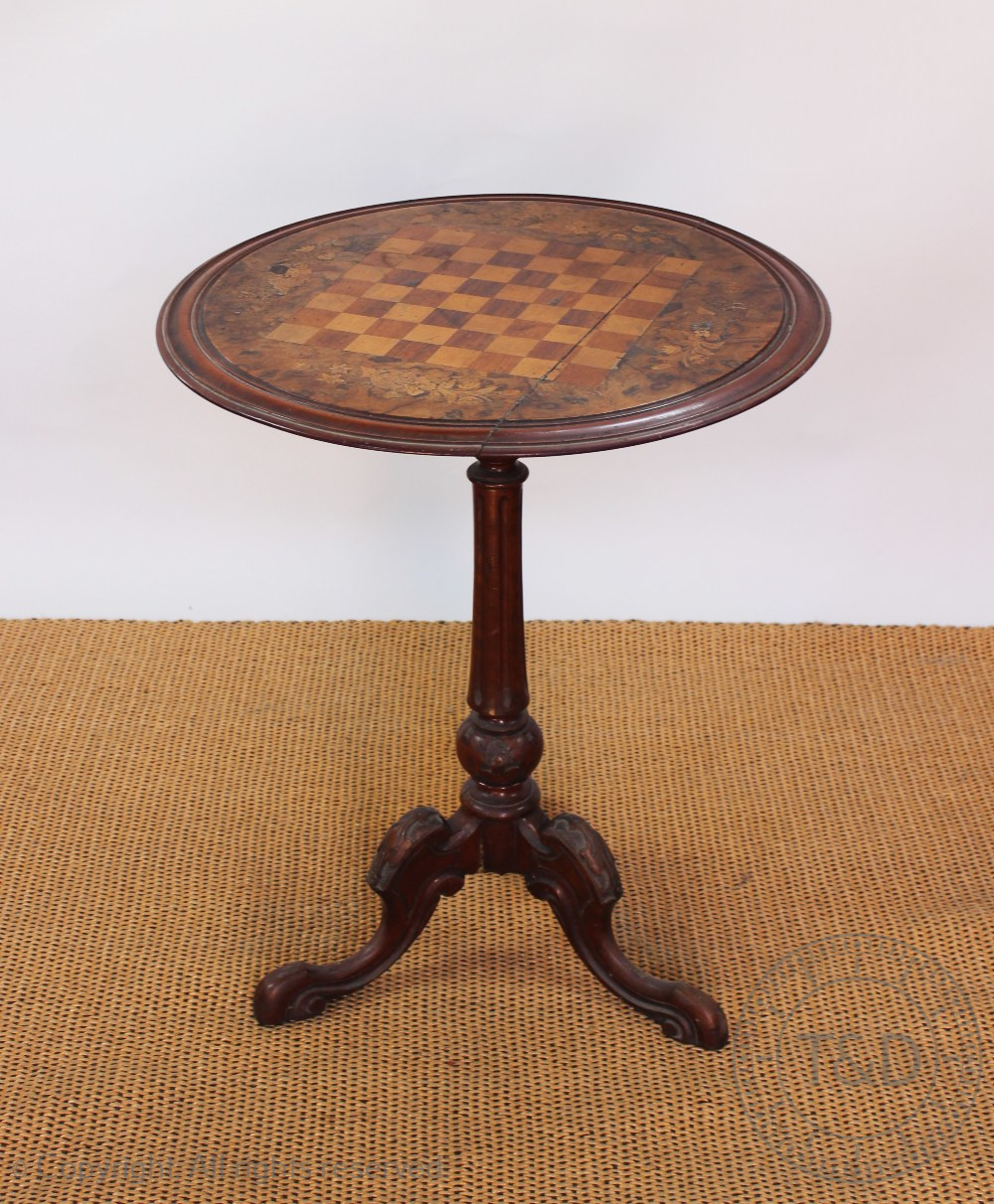 A Victorian inlaid walnut games table, with circular top, on carved tripod base,